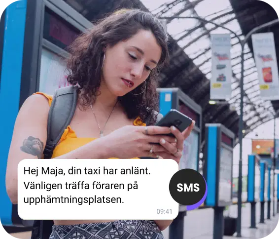 Flicka med en ryggsäck på stationen kontrollerar ett SMS om sin ankommande taxi