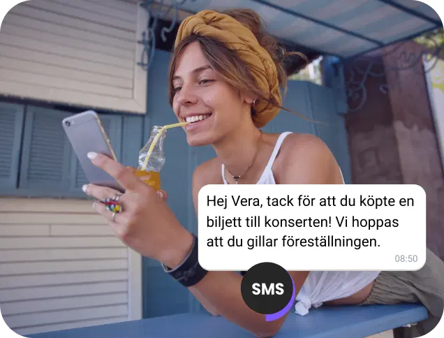 Flicka som dricker juice på gatan kontrollerar en SMS-bekräftelse för en konsertbiljett